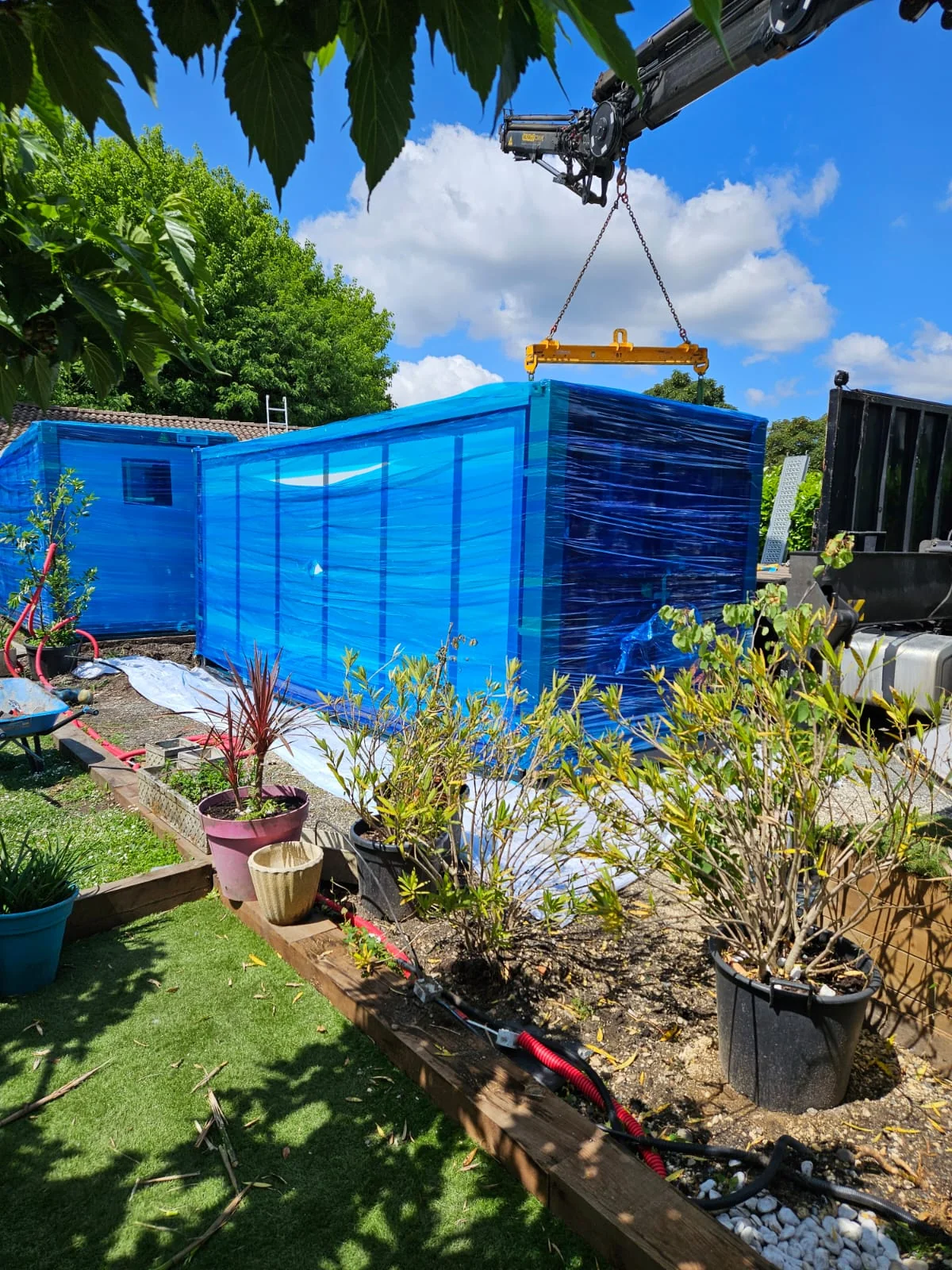 crane truck unloading a wrapped 20ft expandable container house at the customer site in France
