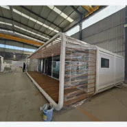 40ft white Apple Cabin with full-length covered pergola and wood-look veranda in factory