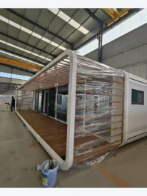 40ft white Apple Cabin with full-length covered pergola and wood-look veranda in factory