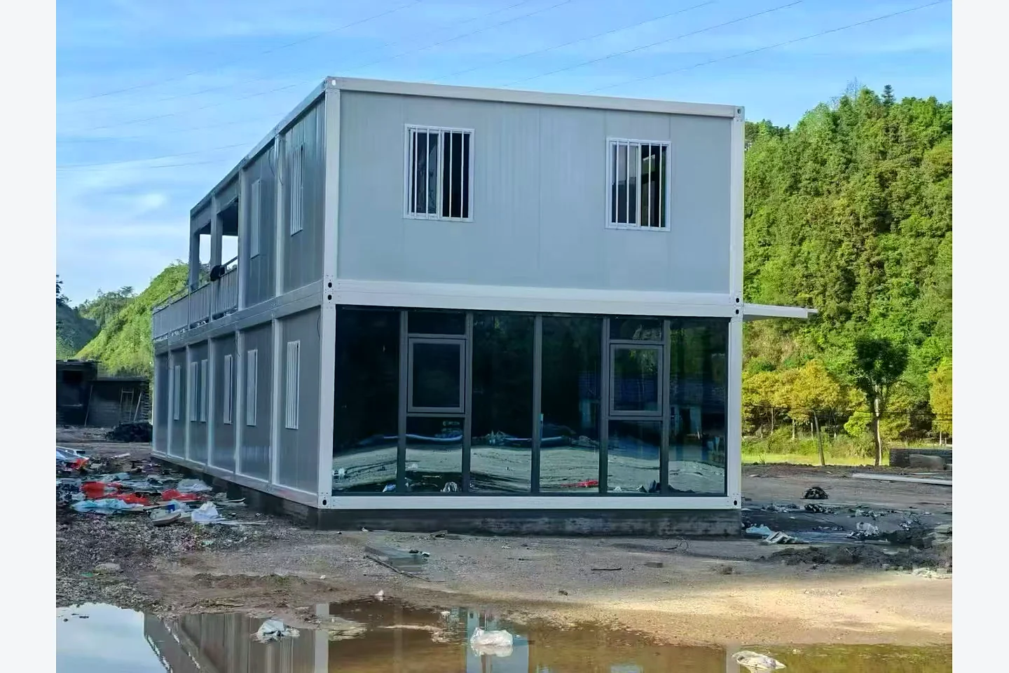 glass-front end view of a two-storey modular container building installed on a hillside