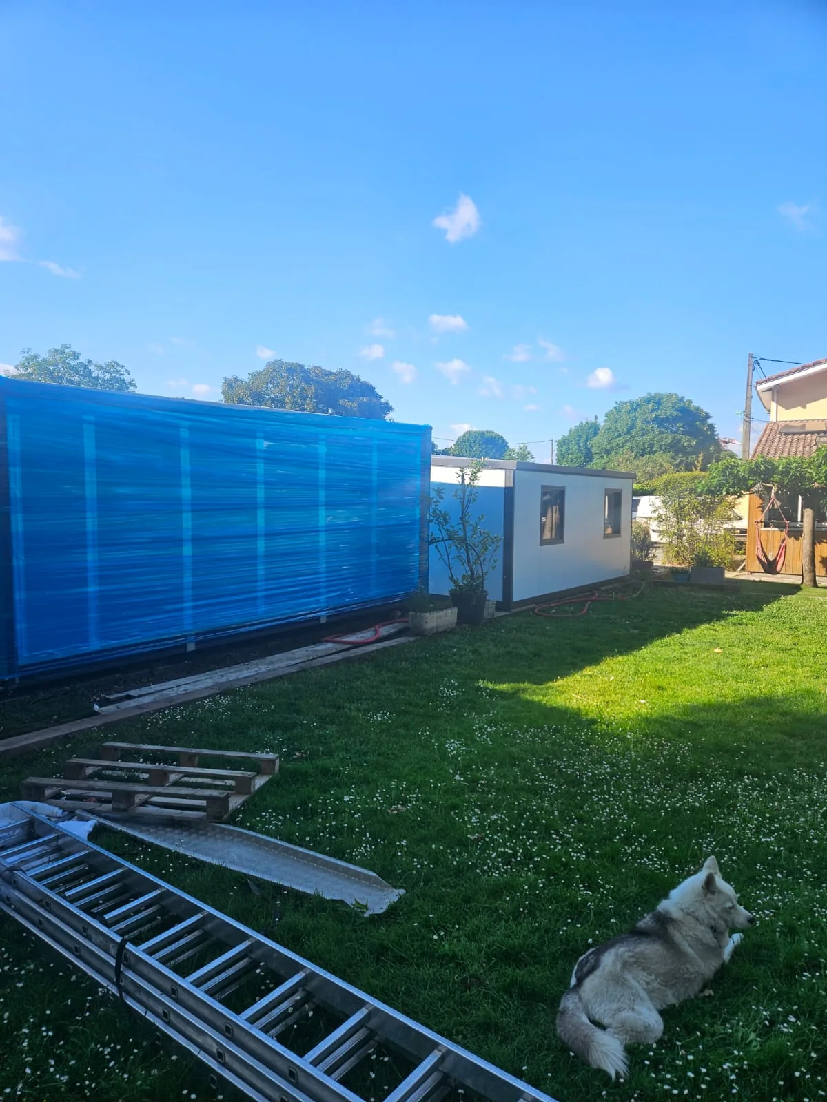 two 20ft expandable container houses at different installation stages in a garden in France