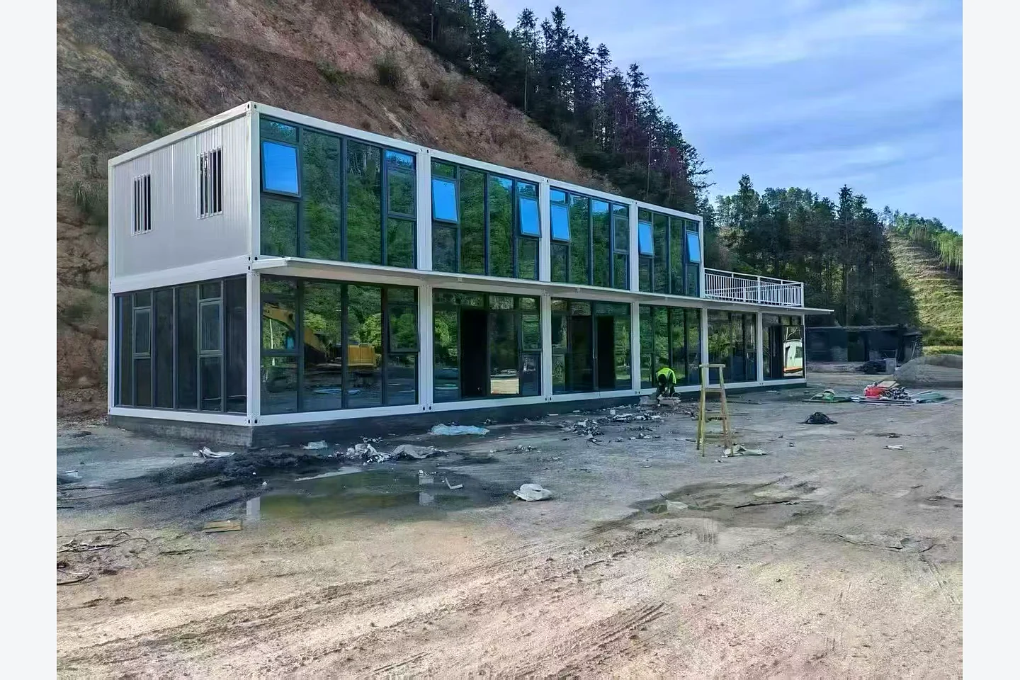 two-storey quick-assembly container house with panoramic glazing at a mountain project site
